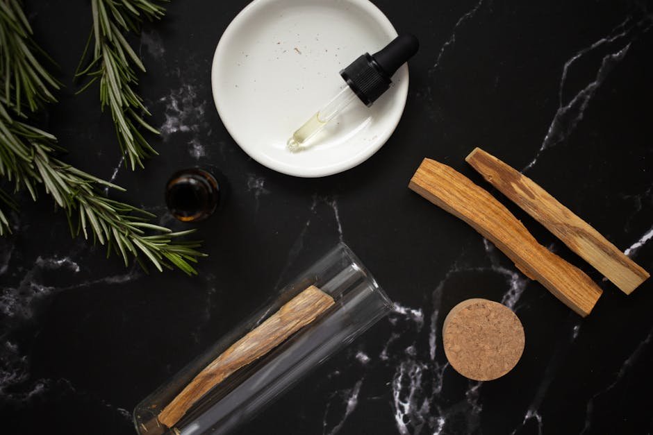 A flat lay of essential oils and natural herbs on a dark marble surface, perfect for aromatherapy and wellness themes.
